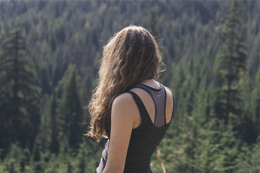 Woman with long curly hair hiking in pine forest