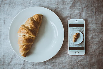 Flat lay of croissant on plate with smartphone photo
