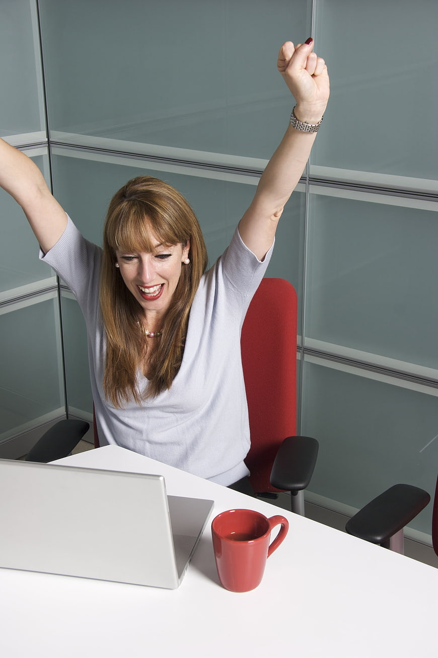 Happy Businesswoman Celebrating Success at Office Desk