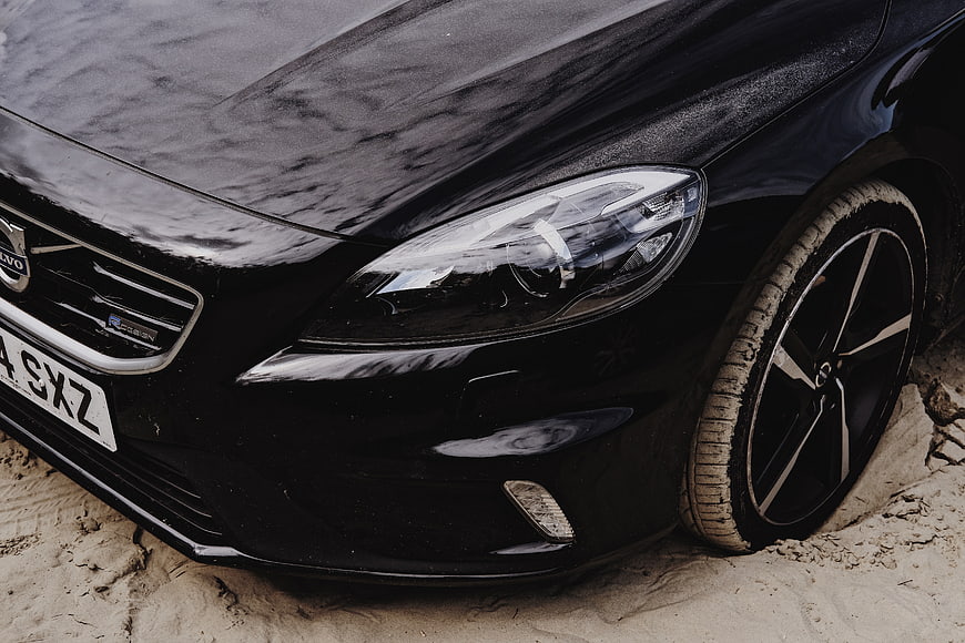 Close-up of black Volvo car stuck in sand
