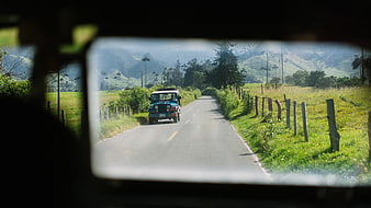 Jeep driving on rural road through green mountains