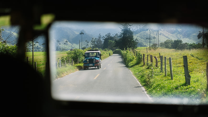 Jeep driving on rural road through green mountains