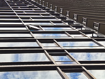Modern glass building facade with sky reflections