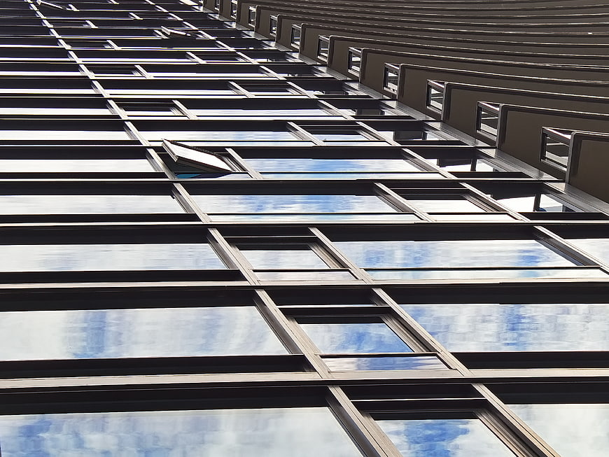Modern glass building facade with sky reflections