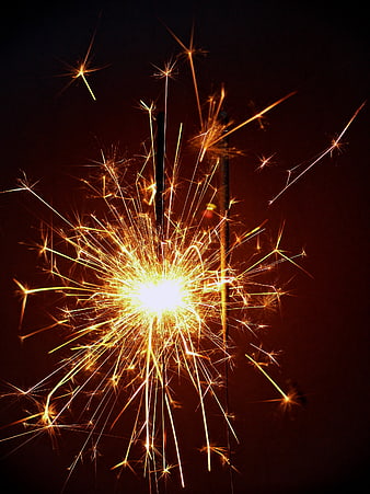 Burning Sparkler with Golden Sparks Against Dark Background