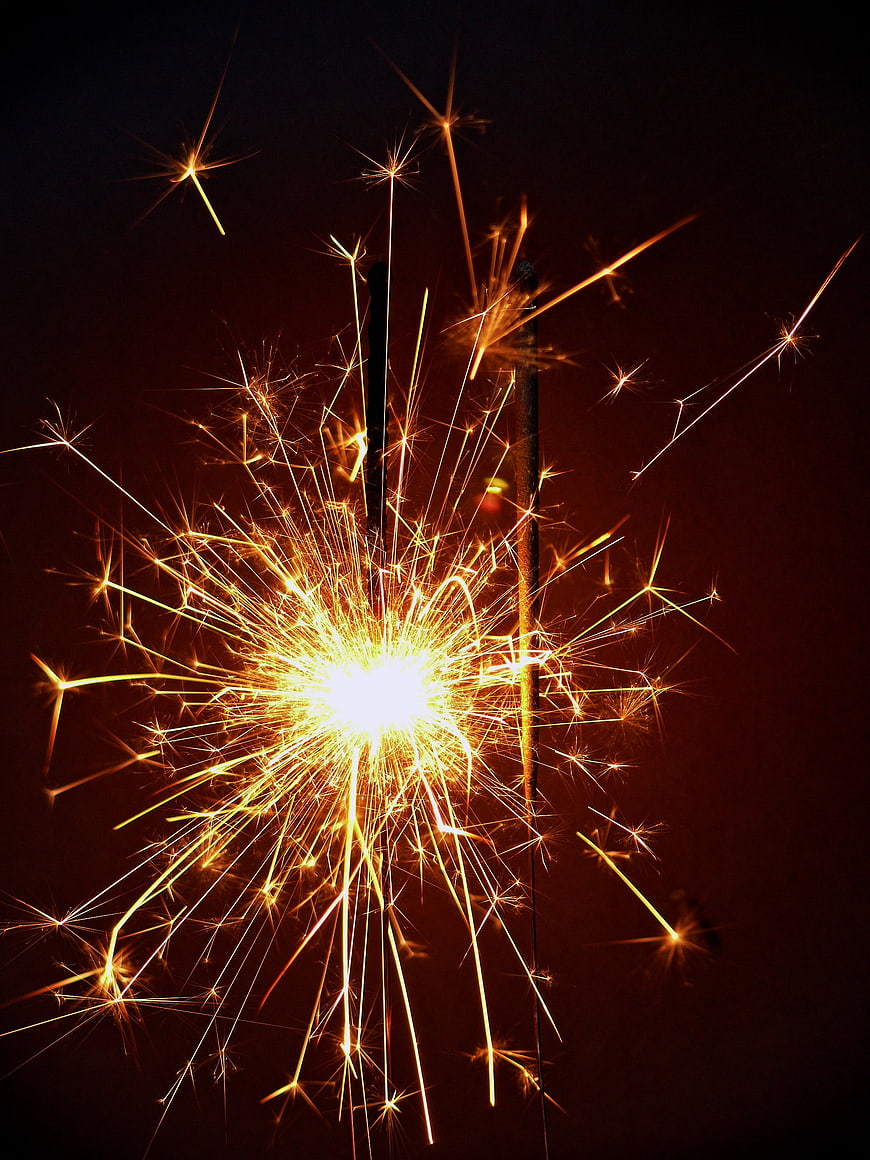Burning Sparkler with Golden Sparks Against Dark Background