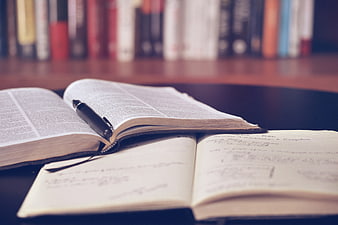 Open Bible and Notebook with Pen on Desk