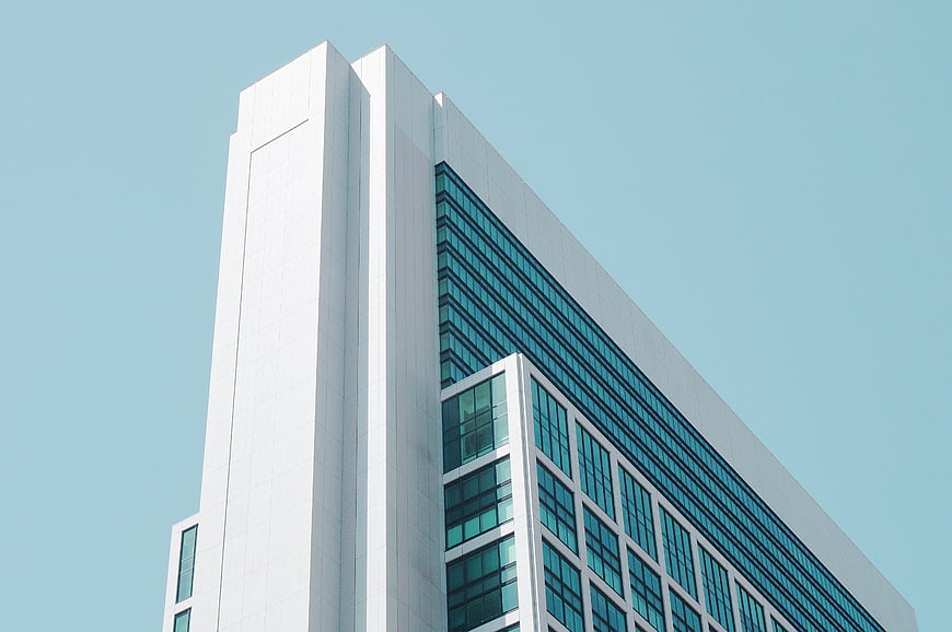 Modern white office building with blue glass windows against sky