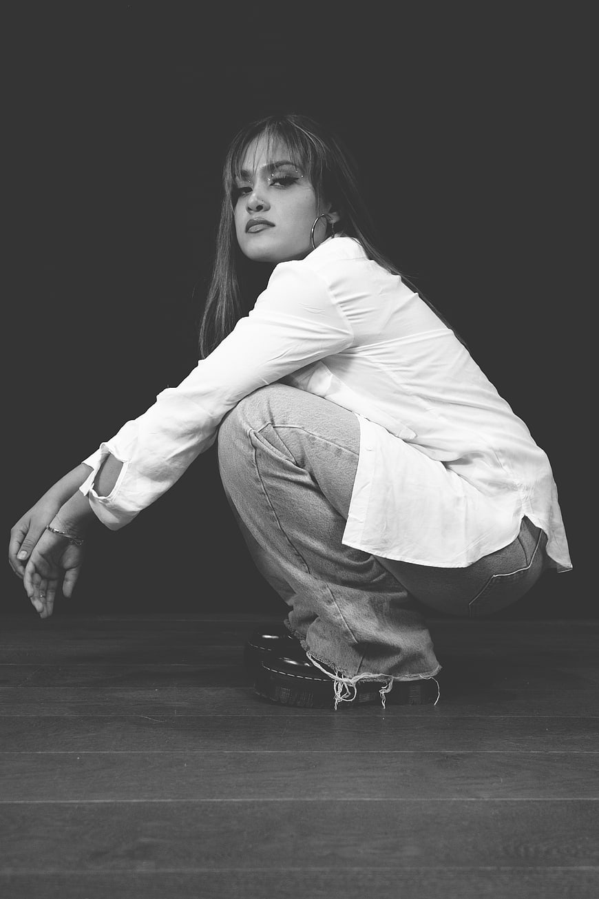 Black and white portrait of a young woman crouching in a studio