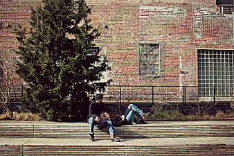 Couple relaxing on wooden steps against brick wall