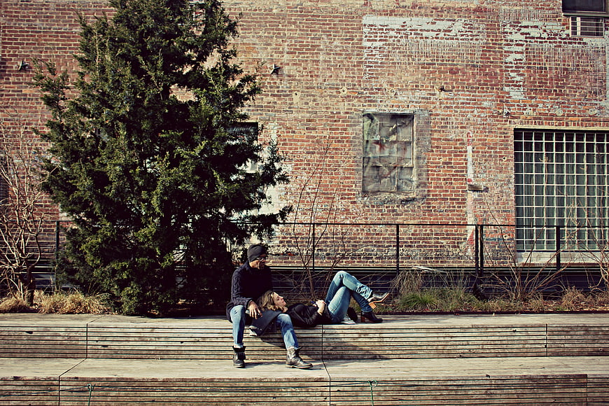 Couple relaxing on wooden steps against brick wall