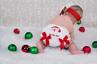 Cute baby crawling in Christmas diaper with ornaments