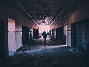 Silhouette of person walking down abandoned hallway