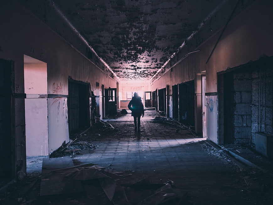 Silhouette of person walking down abandoned hallway