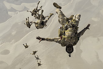 Military Paratroopers Freefalling Over Desert Landscape