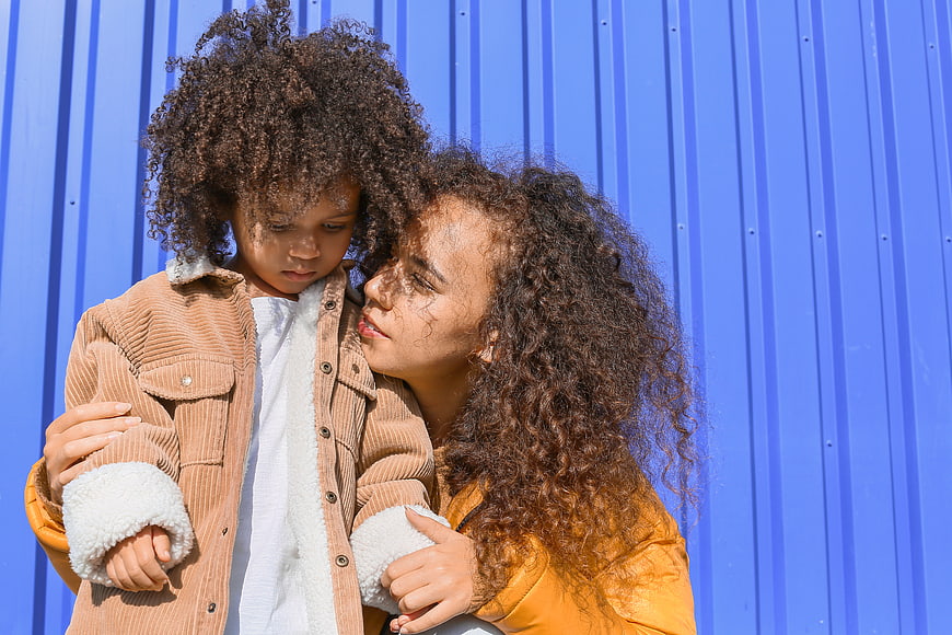 Mother comforting child against blue wall