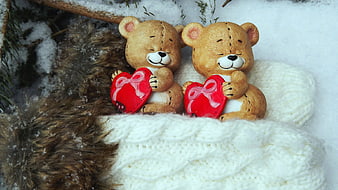 Cute teddy bears holding red hearts in winter snow