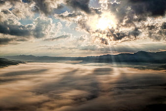 Sun rays breaking through clouds over sea of clouds in Aso Caldera