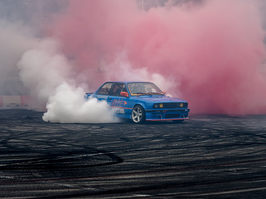 Blue BMW Drifting Car With Pink Smoke On Asphalt Track
