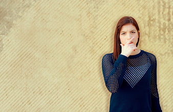 Young woman making shushing gesture against textured beige wall