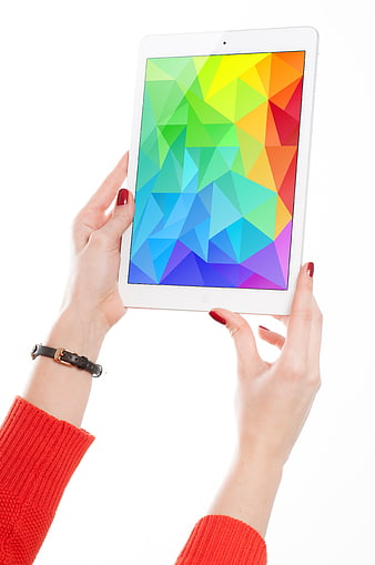 Hands holding white tablet with colorful geometric screen on white background