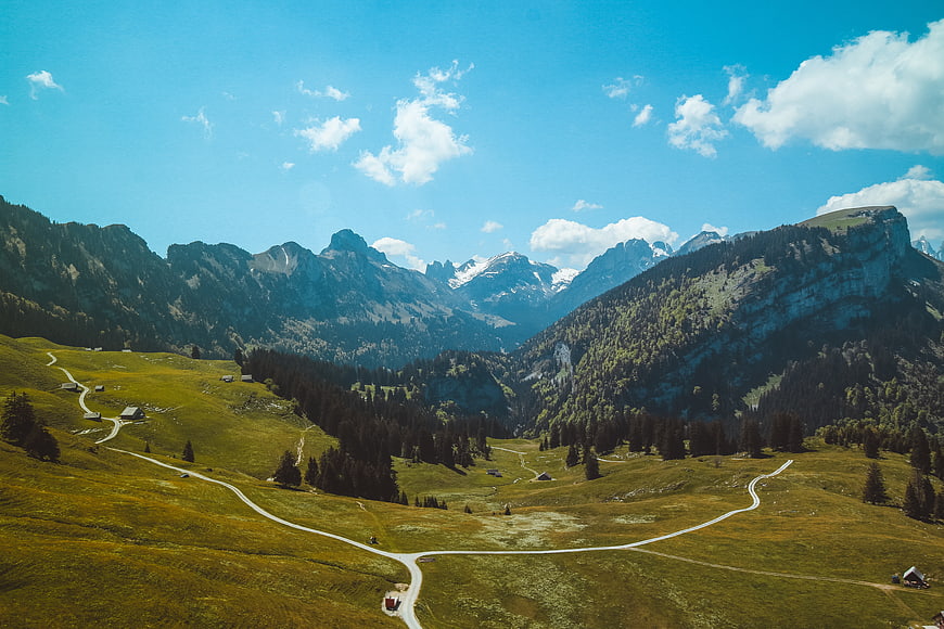 Scenic Alpine Valley with Winding Paths and Snow-Capped Mountains