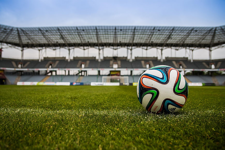 Soccer Ball on Green Grass Field in Empty Stadium