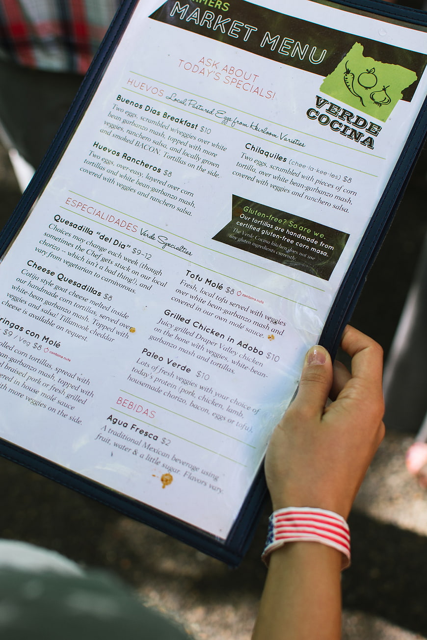Hand holding Verde Cocina market menu with breakfast specials
