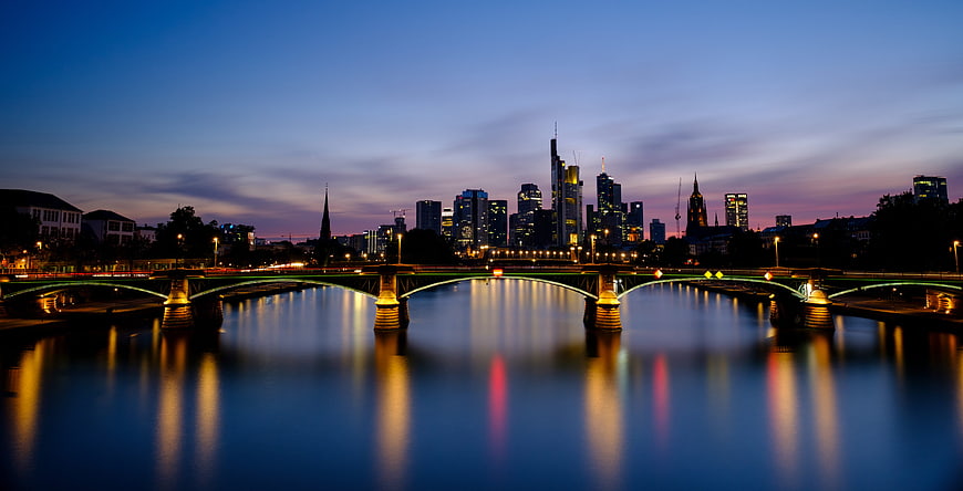 Frankfurt skyline and bridge at twilight with water reflections