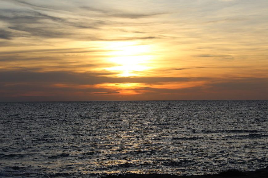 Golden sunset over calm ocean with textured clouds