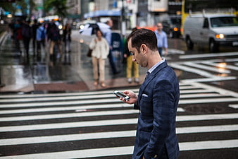 Businessman in Blue Suit Checking Smartphone on City Crosswalk