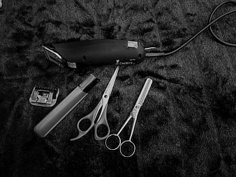 Black and white pet grooming tools on dark fur background