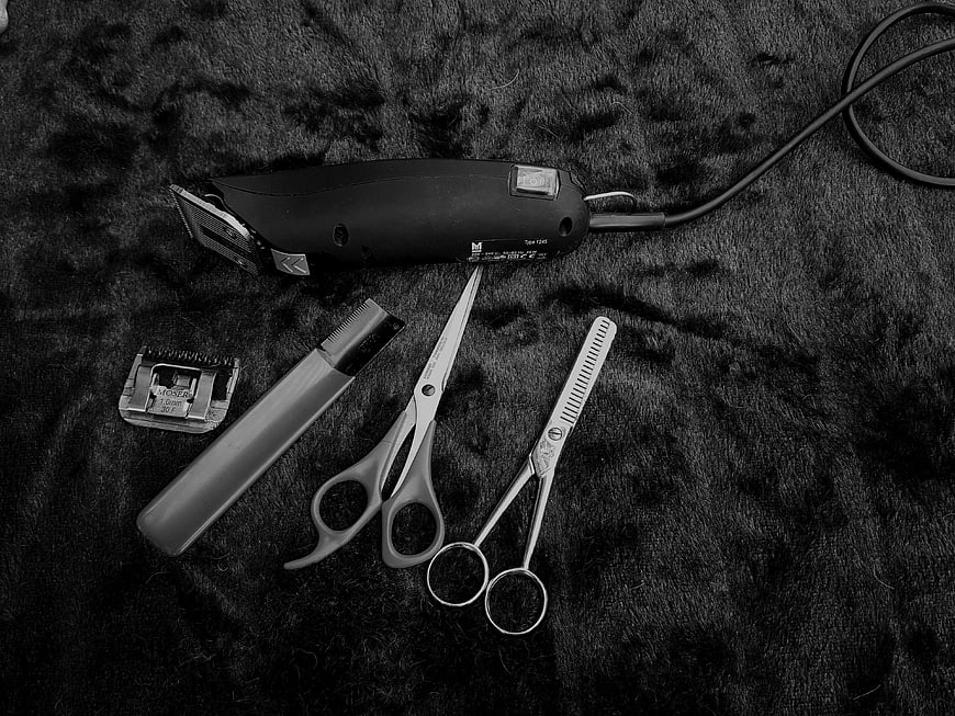 Black and white pet grooming tools on dark fur background