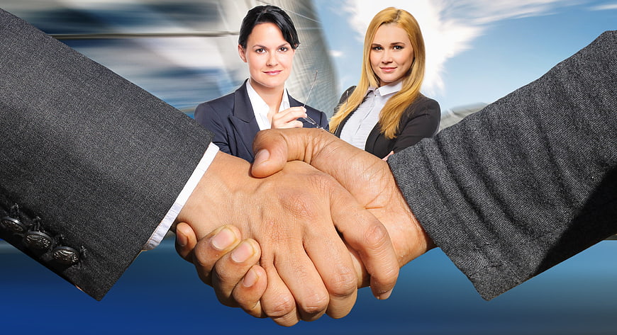 Business Handshake With Two Professional Women In Corporate Office Background