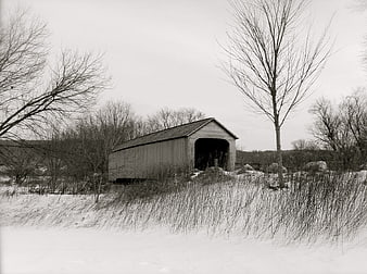 Black and white winter landscape with a rustic covered bridge