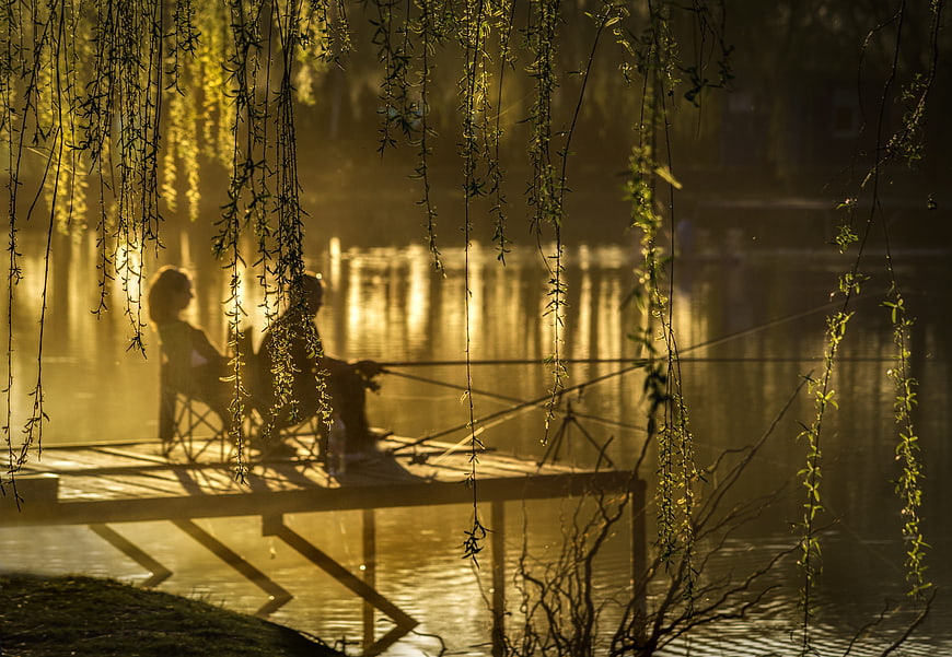 Two Anglers Fishing on a Misty Lake Pier at Golden Hour