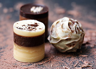 Gourmet chocolate truffles and layered pralines on rustic surface