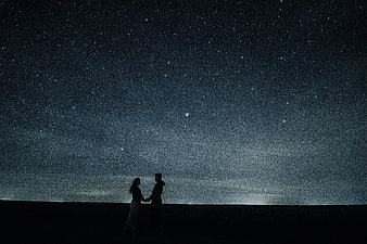 Silhouette of couple holding hands under starry night sky