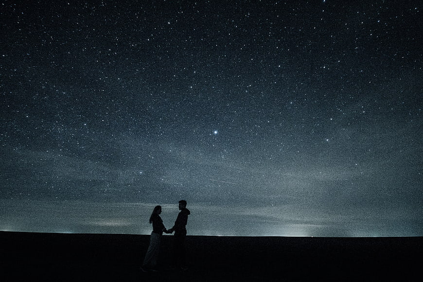 Silhouette of couple holding hands under starry night sky