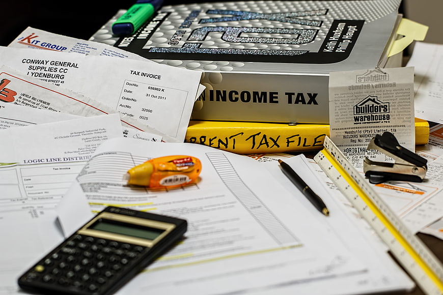 Cluttered desk with tax documents, calculator, and office supplies
