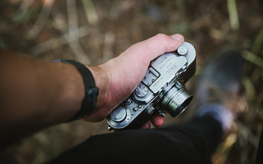 Hand holding vintage Leica camera in forest