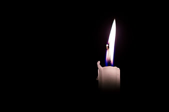 Single lit white candle flame on black background