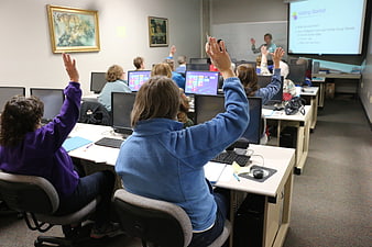 Senior Citizens Raising Hands In Computer Training Classroom