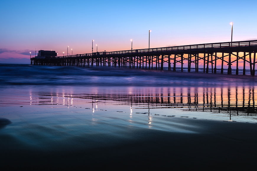 Long Exposure Sunset Pier with Reflections on Wet Sand