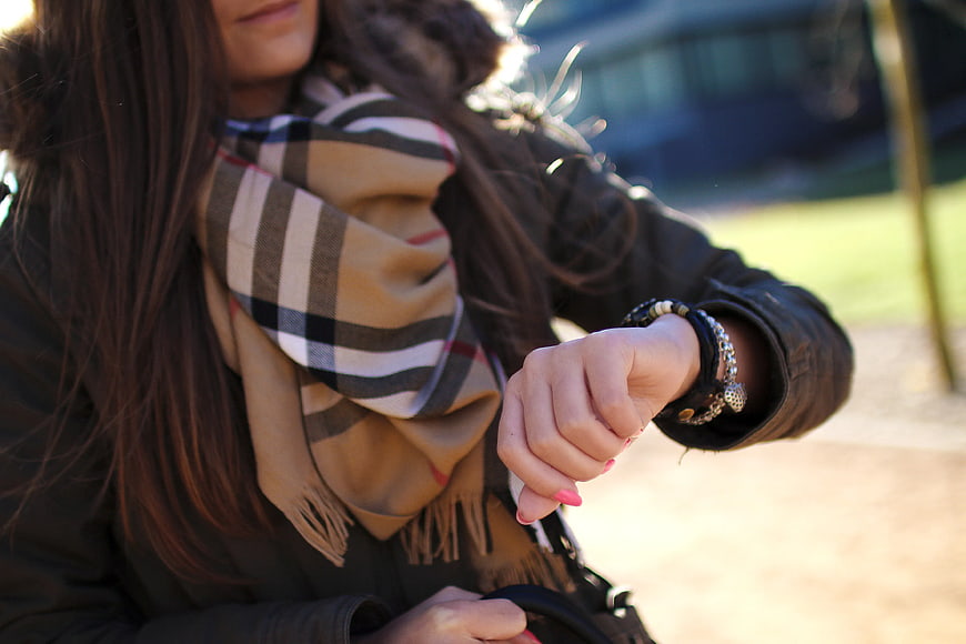 Woman Checking Time on Wristwatch with Plaid Scarf