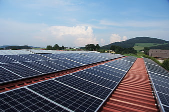 Solar panels on red roof with green hills and blue sky