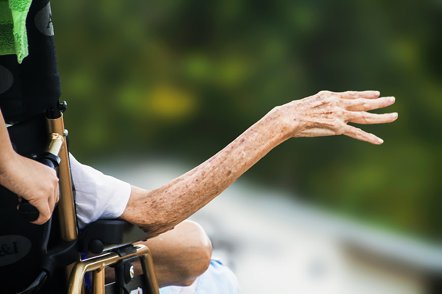Senior in Wheelchair Reaching Out Hand