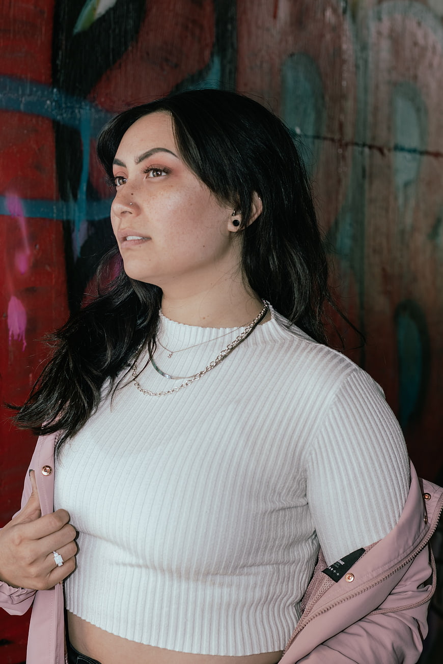 Portrait of young woman with dark hair against graffiti wall