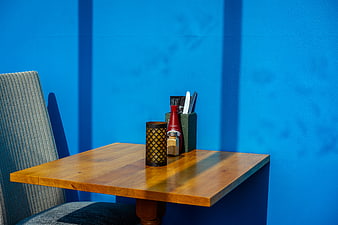 Empty wooden cafe table with condiments against blue wall
