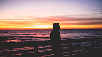 Silhouette of Man Watching Sunset Over Ocean